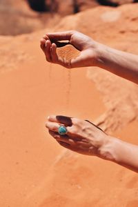 Cropped image of woman holding sand at desert