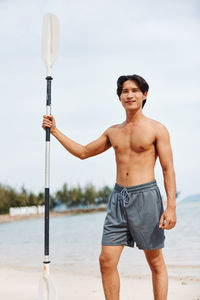 Portrait of shirtless young man standing at beach