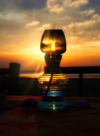 Close-up of lantern on beach at sunset