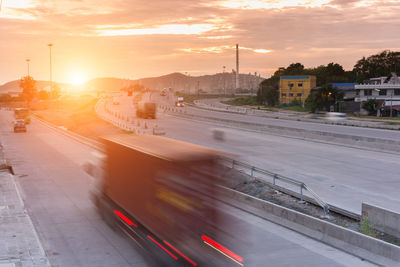 Blurred motion of vehicles on road against sky during sunset