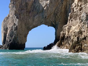 Rock formations by sea against clear blue sky