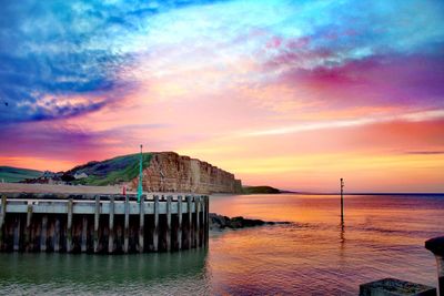 Pier over sea against sky during sunset