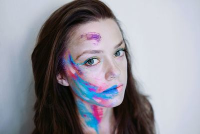 Portrait of beautiful young woman with face paint against wall