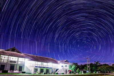 Long exposure image of stars over buildings against sky at night