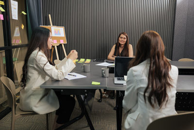 Rear view of woman using mobile phone while sitting at cafe