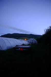 Cars on field against clear sky at dusk