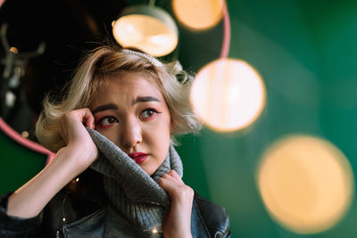 Young woman looking away against wall