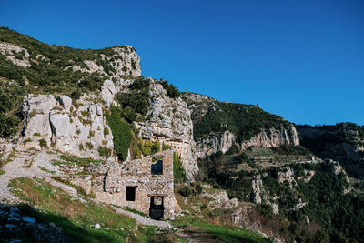 Low angle view of rock formations against clear blue sky