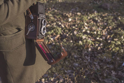 Midsection of woman with antique camera standing on grass field