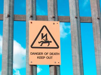 Close-up of warning sign against blue sky