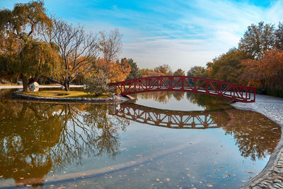 Arch bridge over river against sky during autumn