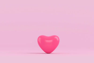 Close-up of heart shape balloon over pink background