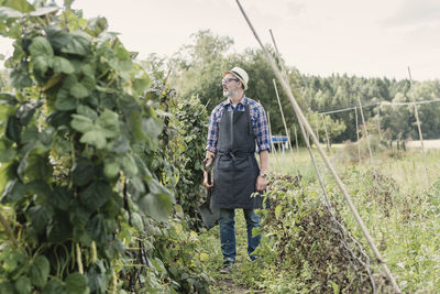 Mature farmer holding shovel and standing in farm