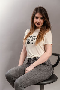 Portrait of beautiful woman sitting against wall