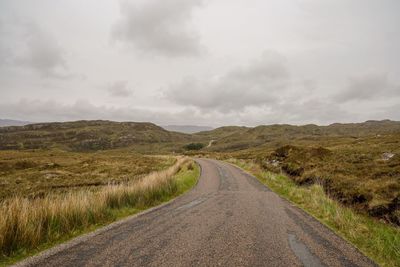 Road amidst field against sky