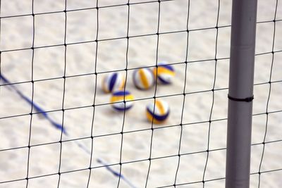 High angle view of volleyballs at beach seen through net