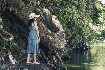 Woman standing on rock against trees