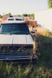 Abandoned car on field against sky