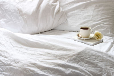 Coffee in cup on bed at home