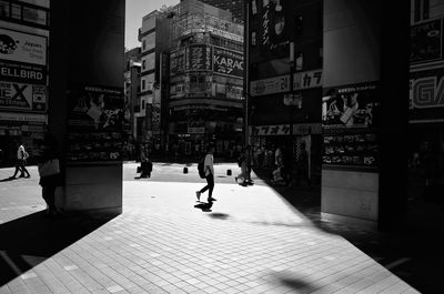 People walking on street amidst buildings in city