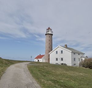 Lighthouse on field against sky