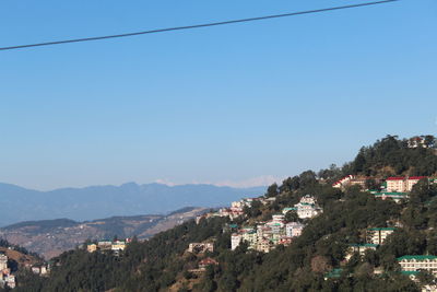 Aerial view of townscape and mountains against clear blue sky