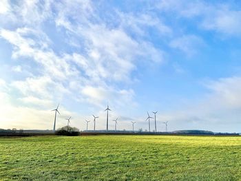 Wind turbines on field against sky