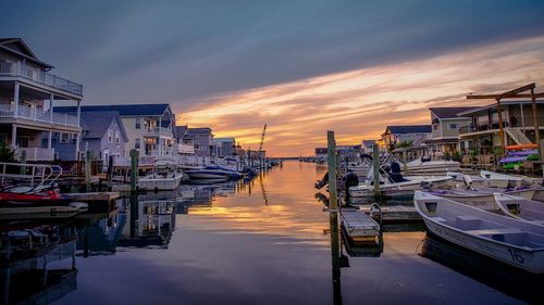 Boats moored at harbor against buildings during sunset