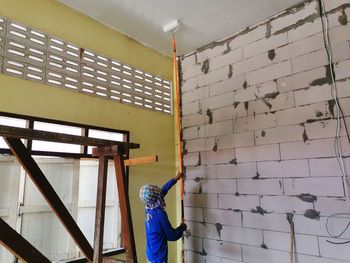 Rear view of man working on wall