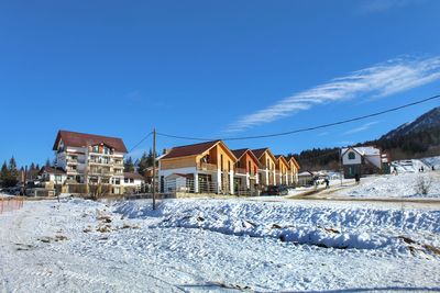 Houses on snow covered field against sky