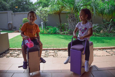 Full length of siblings play on rockers outdoors