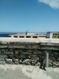 Built structure by sea against clear blue sky