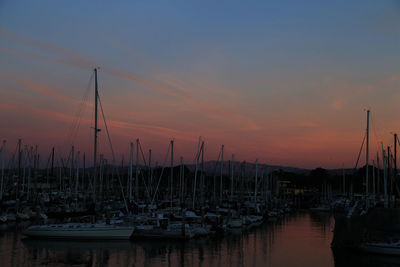 Boats moored in calm sea against dramatic sky
