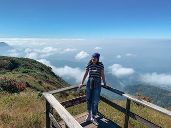 Man standing on railing against mountain
