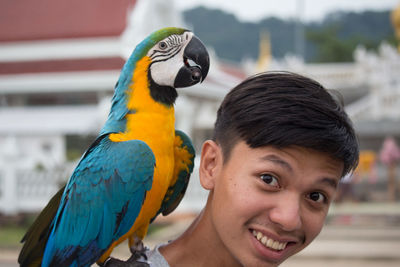 Close-up portrait of smiling man with gold and blue macaw