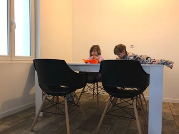 Siblings eating food on table at home