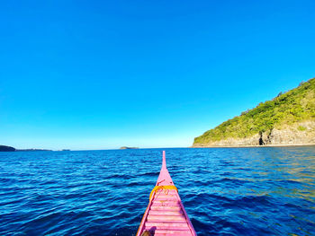 Sailboat on sea against clear blue sky