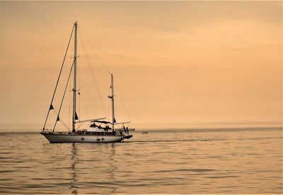 Sailboat sailing on sea against sky during sunset