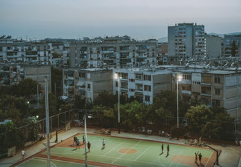 High angle view of people playing soccer on field against buildings