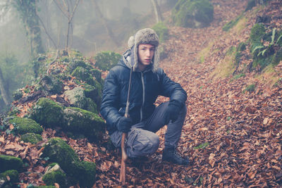 Boy with gun crouching in forest