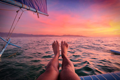 Female relaxing on a sailboat in front of the sunset