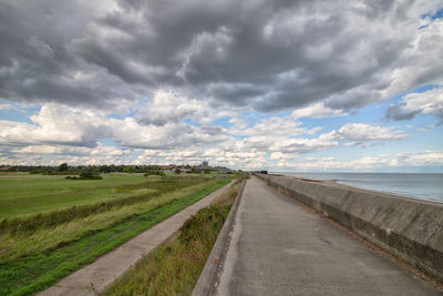 Road amidst field against sky