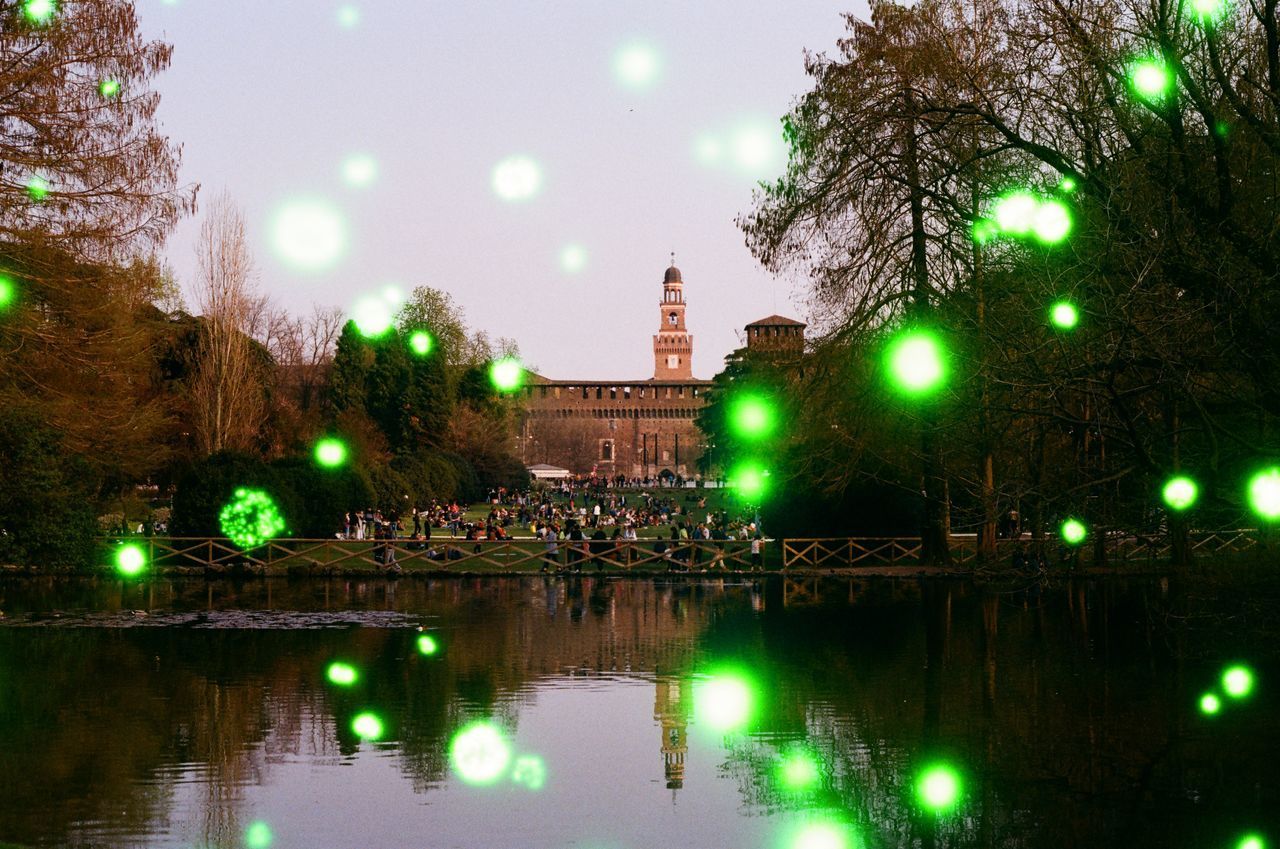 ILLUMINATED CITY BY LAKE AGAINST SKY