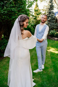 Happy couple standing on grass against plants