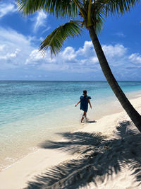 Rear view of woman walking at beach