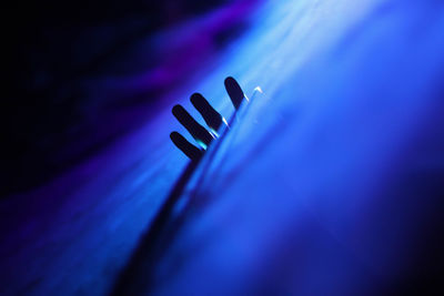 Close-up of hand amidst blue light