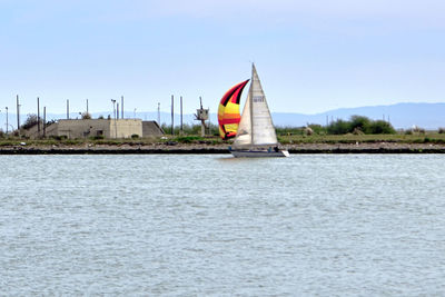 Sailboat sailing on river against clear sky