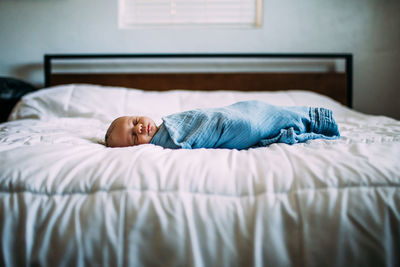 Center portrait of newborn sleeping on bed