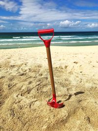 Red umbrella on beach against sky