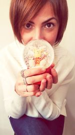 Close-up portrait of young woman holding snow globe